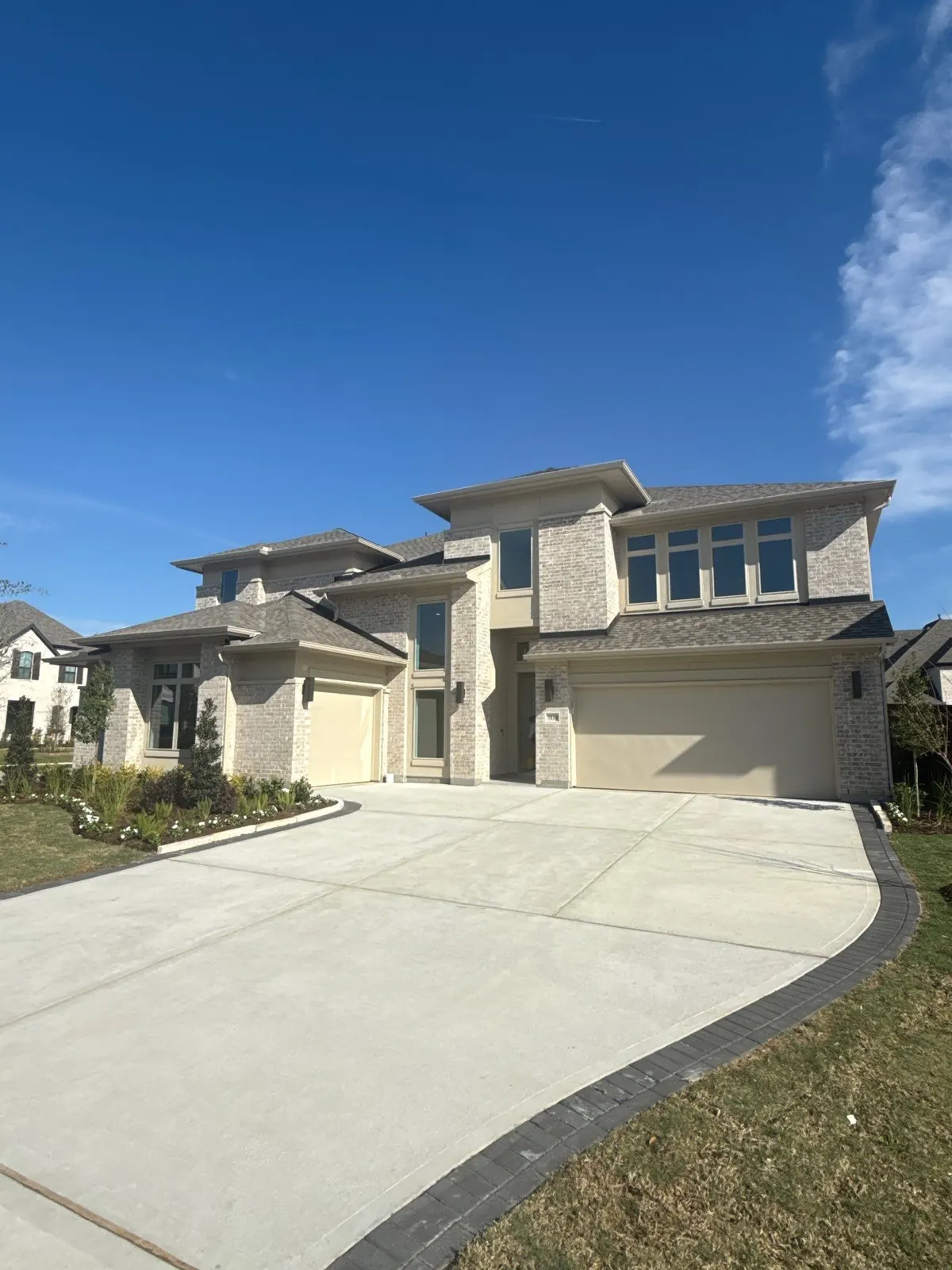 Completed brick home with a broad concrete driveway
