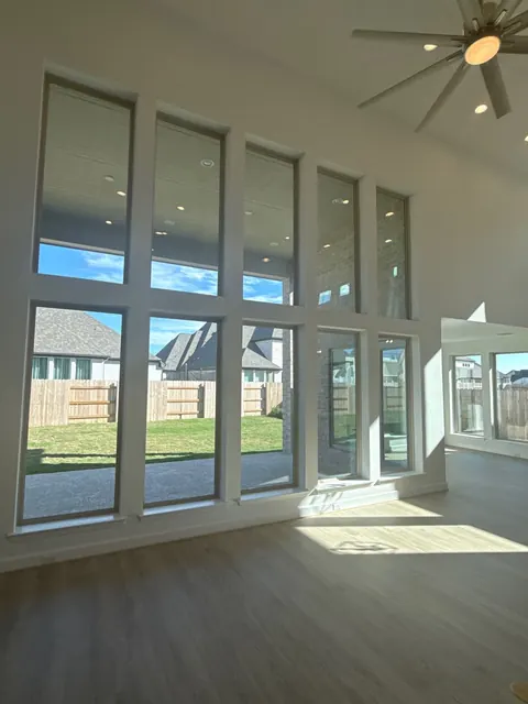 Piso tipo madera iluminado por el sol bajo las ventanas de una sala de doble altura